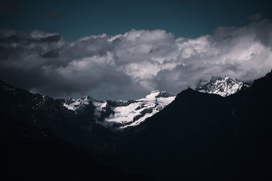 Landscape Of Rocky Mountains Covered In The Snow Under A Dark Cloudy Sky