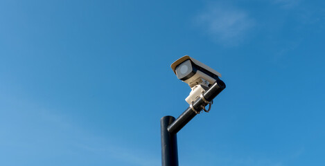 CCTV security cameras on a large post, taken on a sunny bright day with blue sky