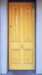 Yellow door with four panels a lock and door handle
