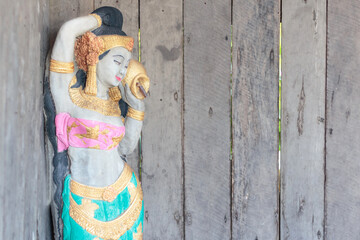 A woman's stucco doll and an old wooden wall.