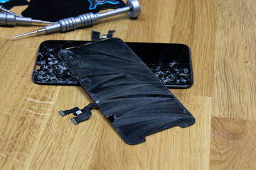 Bangkok, Thailand - 29 May 2021: Close-up shot of the broken screen of the iPhone 11 with tools waiting for repair on a wooden floor.