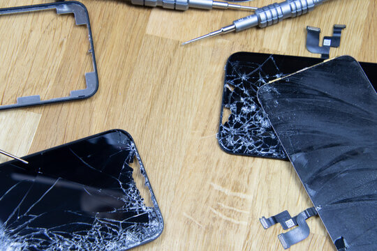 Bangkok, Thailand - 29 May 2021: Close-up shot of the broken screen of the iPhone 11 with tools waiting for repair on a wooden floor.