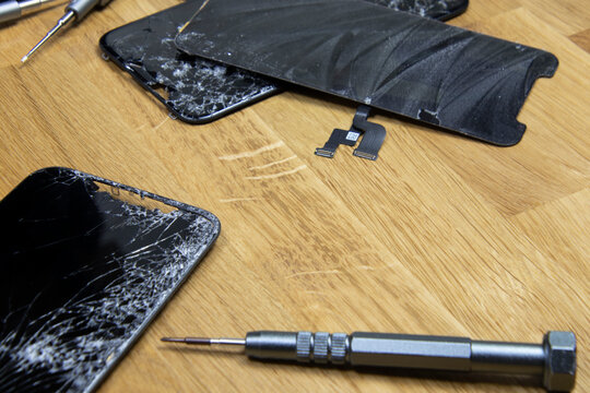 Bangkok, Thailand - 29 May 2021: Close-up shot of the broken screen of the iPhone 11 with tools waiting for repair on a wooden floor.