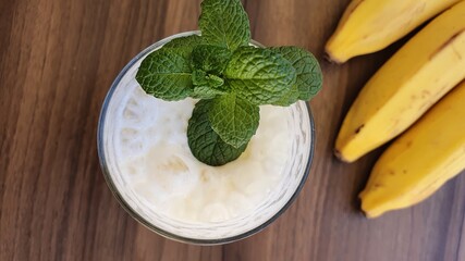 Banana smoothie on the table. Banana shake or banana milkshake is a creamy and nutritious drink. Breakfast and healthy diet. View from above.