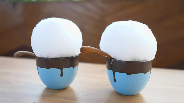 Two little mugs with hot chocolate topped with white cotton candy