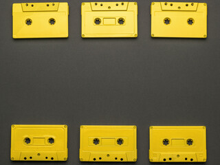 A frame of yellow tape cassettes on a black background. Flat lay.