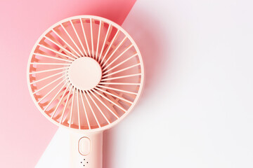 Small portable fan on white and pink background close-up.