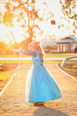 Fototapeta na wymiar Flower girl wearing vibrant blue dress in golden afternoon light