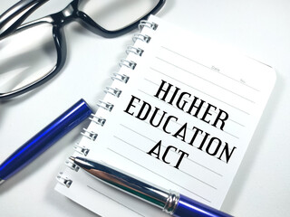 Education concept.Text HIGHER EDUCATION ACT on notebook with glasses and blue pen on a white background.