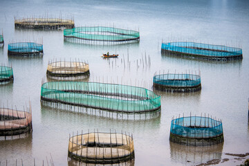 Curved fishing nets - A fisherman sailing among round giant fishing nets on mudflats in Xiapu, China