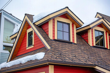 Red rooftop with attic windows under the cloudy sky