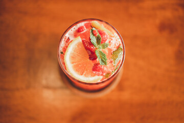 Raspberry with lemonade in glass on wooden background