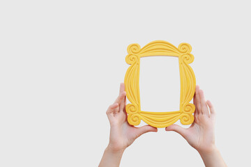 a hand holds a yellow frame from the TV series friends