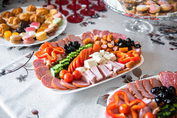A plate with different appetizers, with all kinds of sausages, cheeses and vegetables at an event....