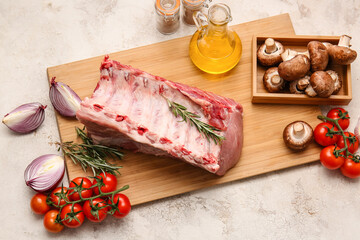 Board with raw pork meat and vegetables on light background