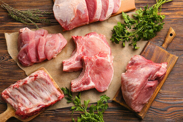 Slices of raw pork meat and parsley on wooden background
