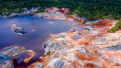 Landscape like a planet Mars surface. Ural refractory clay quarries. Nature of Ural mountains, Russia. The hardened red-brown surface of the earth. Blue lake