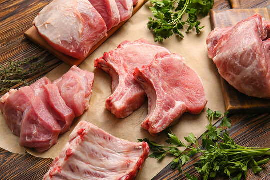 Slices of raw pork meat and parsley on wooden background