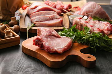 Board with slice of raw pork rib and parsley on dark wooden background, closeup