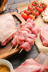 Board with pieces of raw pork meat on dark wooden background