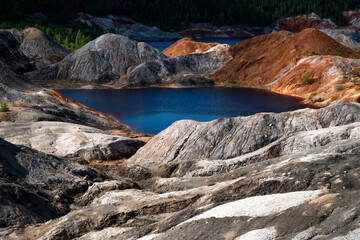 Fototapeta na wymiar Landscape like a planet Mars surface. Ural refractory clay quarries. Nature of Ural mountains, Russia. The hardened red-brown surface of the earth. Blue lake