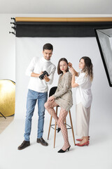 Fototapeta premium Stylist and photographer working with model in studio