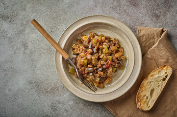 Homemade traditional Sicilian caponata with eggplant, zucchini, tomatoes, olives and ciabatta bread. Top view, copy space