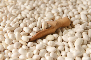 Wooden scoop on raw beans, closeup