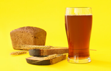 Glass of fresh kvass and bread on color background