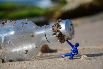 Long lost glass bottle with shells around its mouth on the beach being held up by a figurine