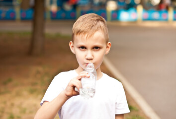 Little boy kid drinking water from a bottle outdoor in a park