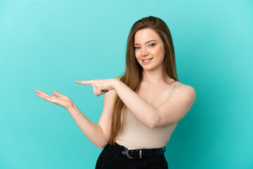 Teenager girl over isolated blue background holding copyspace imaginary on the palm to insert an ad