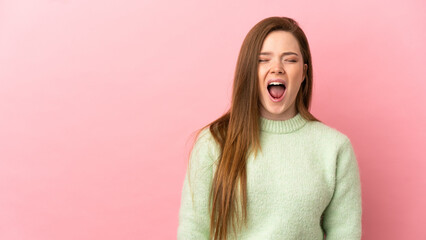 Teenager girl over isolated pink background shouting to the front with mouth wide open