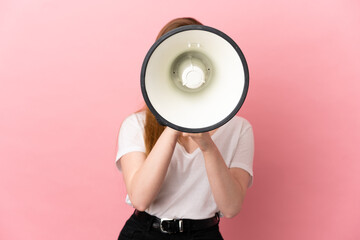 Teenager girl over isolated pink background shouting through a megaphone to announce something