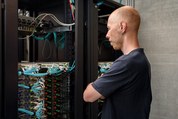 Man data center technician performing server maintenance. Looking to hardware rack