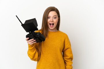 Teenager girl holding a drone remote control over isolated white background with surprise facial expression
