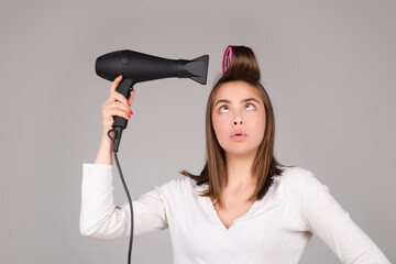 Woman with hair dryer. Funny girl with straight hair drying hair with professional hairdryer. Hairstyle, hairdressing concept.