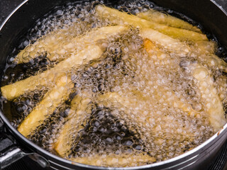 Close up of Frying french fries in the fryer in hot oil on the electric stove in the kitchen. Making homemade french fries.