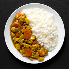 Homemade Japanese Chicken Curry  on a white plate on a black background, top view. Flat lay, overhead, from above.