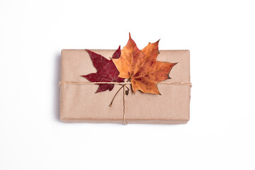 gift in craft paper with autumn leaves on a white background, package, delivery, autumn mood, surprise,