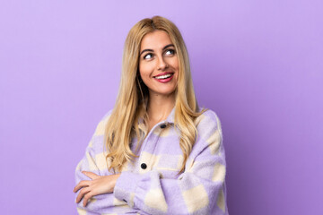 Young Uruguayan blonde woman over isolated background looking up while smiling