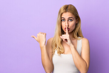 Young Uruguayan blonde woman over isolated background pointing to the side and doing silence gesture