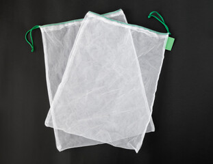 Top view of white reusable mesh bags on black background