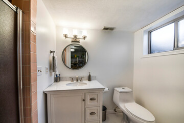 Bathroom interior with window, single vanity sink and one piece toilet bowl