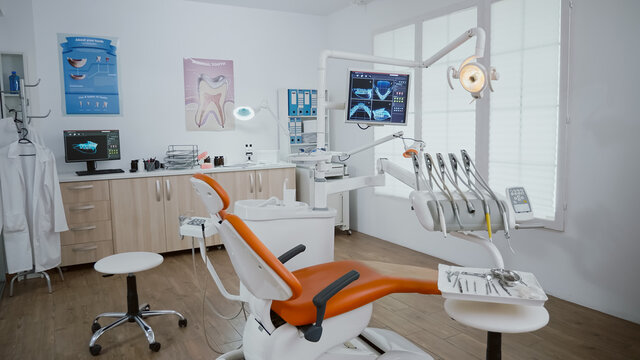 Close up revealing shot of stomatology orthodontic hospital office room with nobody in it prepared for healthcare treatment. Medical cabinet with teeth xray images on monitor and dentistry tools