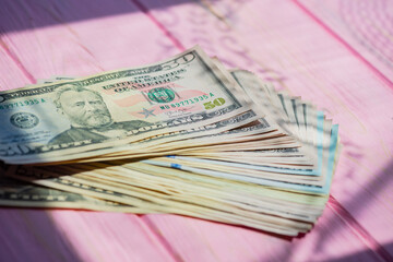 Closeup American cash banknotes. Dollars on a pink wooden background. Finance concept.