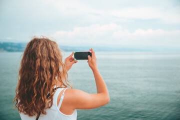 woman taking picture of the sea on the phone