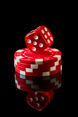 Red casino dice and chips isolated over black reflective background