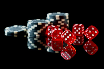 Red casino dice and chips isolated over black reflective background