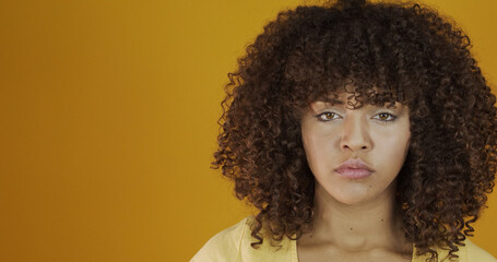 Beautiful serious brunette model on yellow. Curly hair. Brazilian young woman.